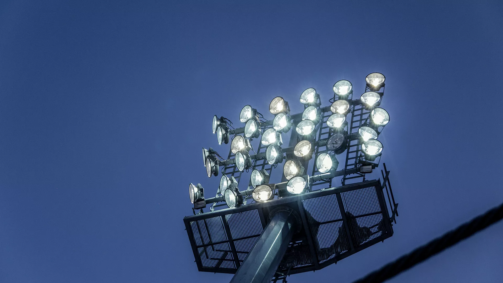 Flutlichtmast der Skiflugschanze Oberstdorf mit eingeschalteten Strahlern vor dem Abendhimmel